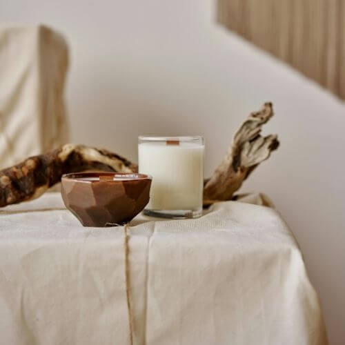 Eléments de décoration sur une nappe beige : bougie et morceau de bois flotté